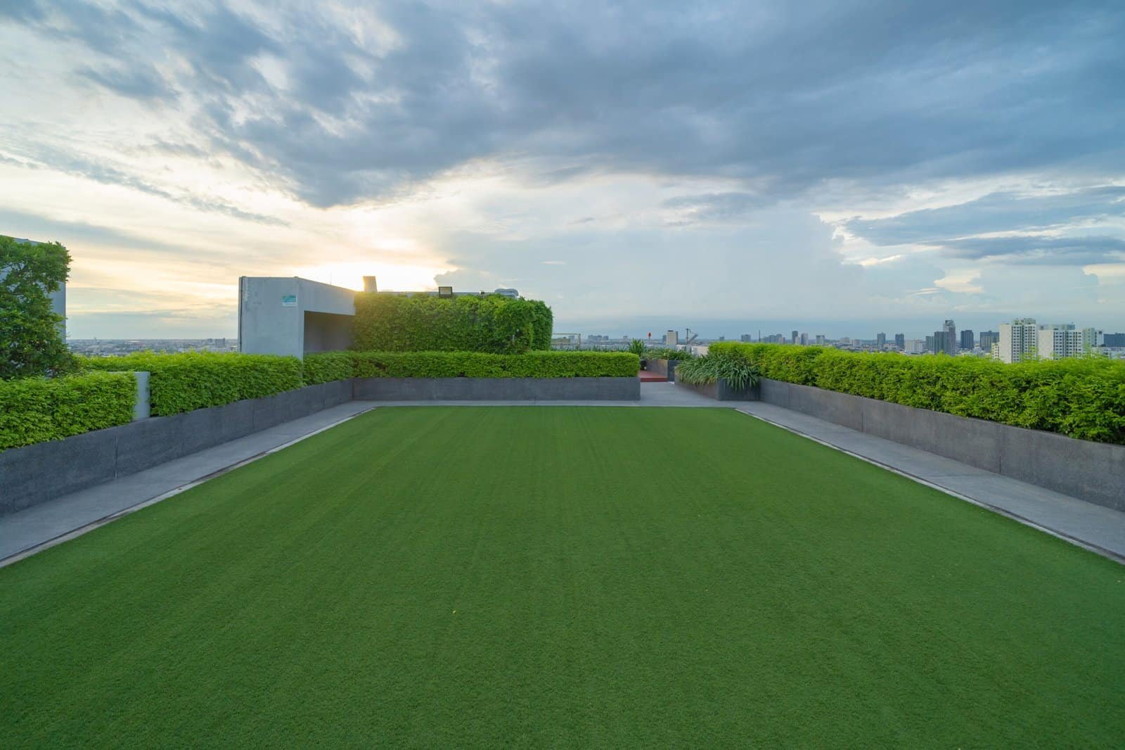 Jardín en azotea con césped artificial, vista panorámica de la ciudad, diseño de paisajismo moderno, mantenimiento de áreas verdes en azoteas, servicios de paisajismo en áreas urbanas.